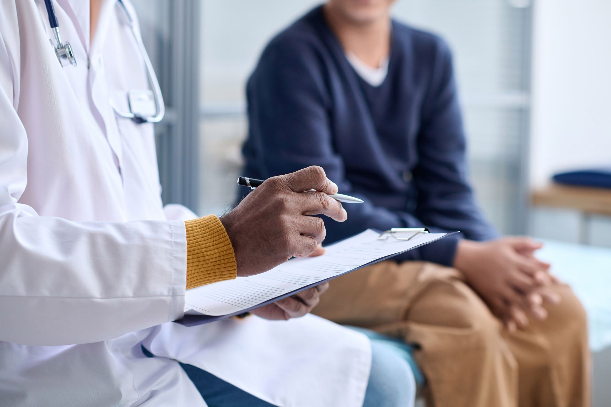 Clinician taking notes while talking with a patient
